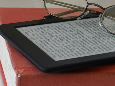 Kindle and glasses on a print book