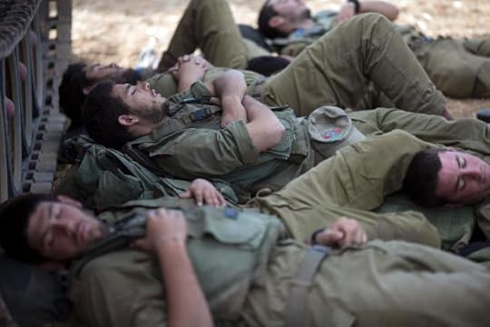 Israeli soldiers sleep in the shade of a military vehicle near the Israel-Gaza border early Tuesday, July 15, 2014.