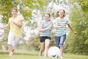 Three young girl friends playing soccer