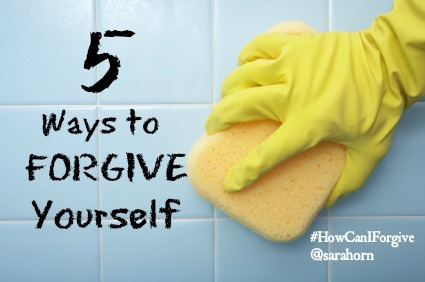 Rubber-gloved hand scrubbing bathroom tile with a sponge