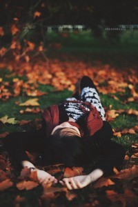 girl lying on grass with fall leaves