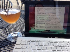 patop on outdoor table with glass of beer beside it