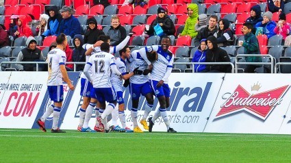 Lance Laing is mobbed by his FCE teammates after scoring directly off a corner kick.