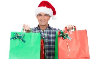 Happy man with Santa red hat holding Christmas bags. Isolated on