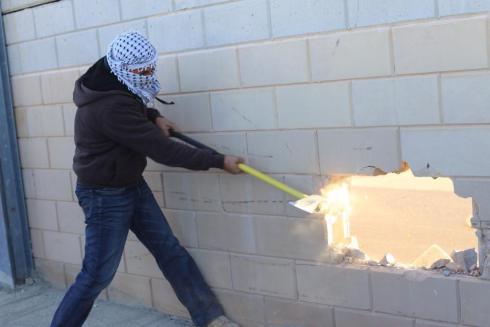 Palestinian smashes hole in the separation wall near Jerusalem.
