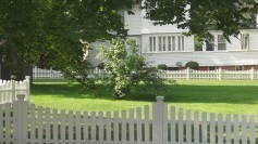 Fences on a lawn, private residence in background, signifying dividers and privacy.