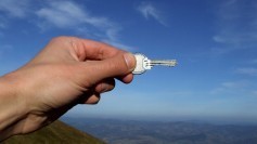 Hand holding key against sky