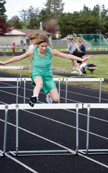 Photo of girl jumping over hurdle