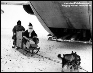 Santa Claus and his sled loaded with gifts come dashing from the back of a C-123 airplane at Savoonga on St. Lawrence Island in 1963.