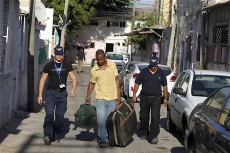 Israeli immigration officers escort an African migrant in south Tel Aviv