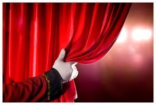 White gloved hand pulling back red theatre curtain1372012162644