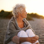 Old woman sitting on the beach looking away at copyspace