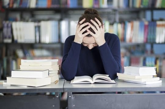 Female college student stressed and overwhelmed and trying to study at the school library. © Antonio_Diaz via iStock.