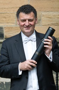 Steven Moffat holding the season finale script that is written on a papyrus scroll.