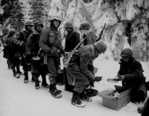 Men of the US 347th Infantry Regiment taking a meal break while en route to La Roche, Belgium, 13 Jan 1945. (US National Archives)