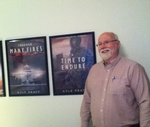 Kyle Pratt with posters of Through Many Fires and A Time to Endure.