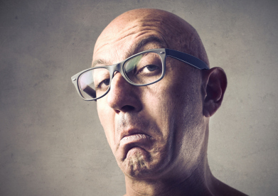 Bald man with glasses and a snobbish expression