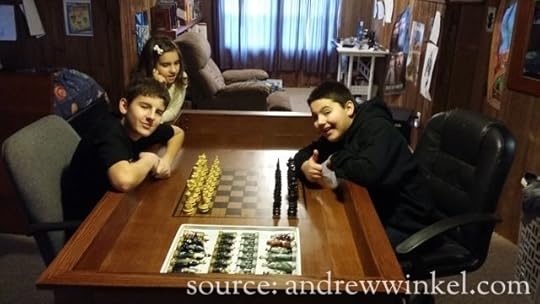 Alex and Bryan ready to start a game of chess while Anna watches.