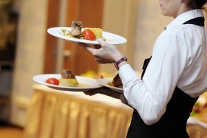 Waitress carrying three plates with meat dish