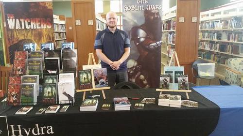 Here is the basic setup I use at most live events. The banner is behind me and I use 1 or 2 stands to show off my books. I have free bookmarks sitting in front and copies for people to pick up and check out. The table is also covered with the Hydra Publications logo and banner to add further legitimacy. This photo is from a local ComiCon at a small library that drew about 3,000 people. I sold out of books.