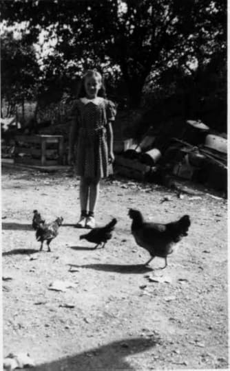 In the image, a young girl poses in a polka dot dress with a white collar. In front of her are three chickens. The young girl may be Myrtle Dezemo who would be approximately age 8. On the back of the photograph is written 