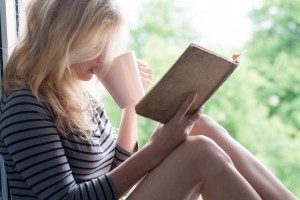 Woman lying in a garden and enjoying book reading