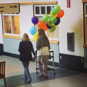 photo of two women in a hospital corridor with balloons