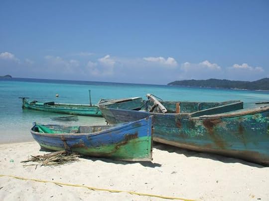 Three old fishing boats on the shore of a beach.