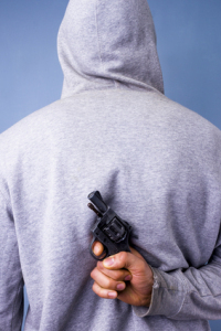 Hooded man hiding gun behind his back