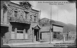 This postcard from 1912 shows the first lodge of the Arctic Brotherhood, with driftwood placed on the façade, as well as a mountain behind with the letters AB prominently painted on its side in Skagway. A note on the back of the photo states: “Only ‘sourdough’ Alaskans may be members of this lodge.”