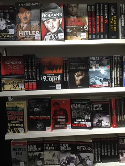En bokylle med masse sorte og røde bøker med dystre bilder og knyttede never med titler som Hitler, Eichmann og 9. april. Doom and gloom.
