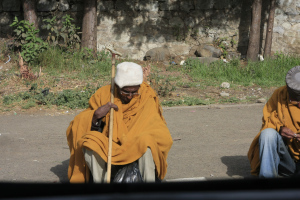 A beggar in the street, awaiting the end of mass.