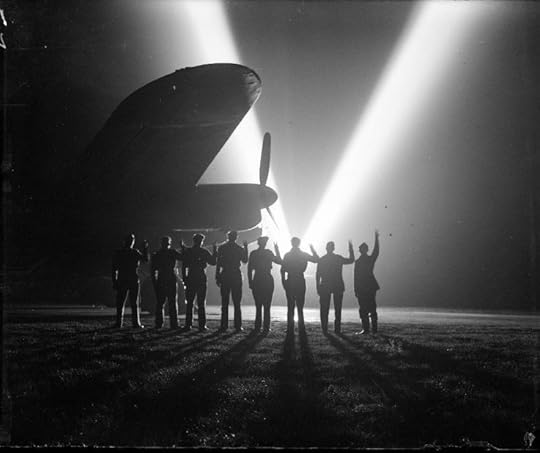 Ground crew on a RAF Bomber Command station in Britain return the 'V for Victory' sign to a neighboring searchlight crew. Silhouetted is the nose of a Lancaster bomber. (Imperial War Museum)