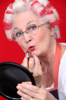 Grandmother with her hair in rollers applying lipstick
