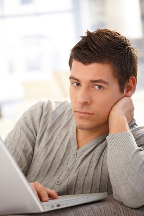 Portrait of handsome young man with laptop computer, looking at camera.