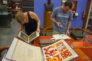 Letterpress printers Paul Moxon and Val Lucas, consulting materials from Watson Library's Special Collections.