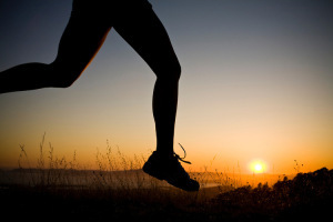 A silhouetted woman runs at sunset.