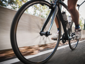 Detail of a road bike with a cyclist pedaling on a road. Photo is taken in low angle composition.