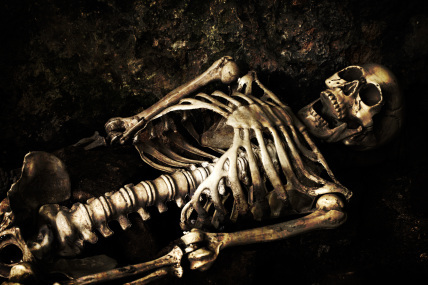 Skeleton lying in shallow grave at Halloween