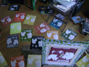 Here’s my print-covered floor and the screen upright in the hinge clamps of my t-shirt press just before I went to wash the ink out of it. 