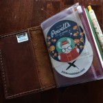 This shows something Midoris don't have -- the sewn-in pocket. It's very handy, though it does thicken the cover. Also in this pic, a Midori passport-size zipper pouch insert.