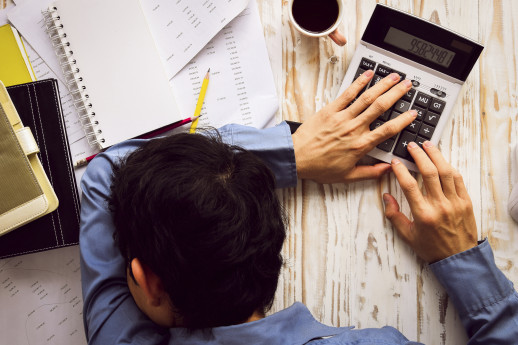 Businessman asleep at office desk with finance sheet calculator and coffee.(concept for overworked)