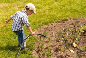 Little boy playing with garden hose