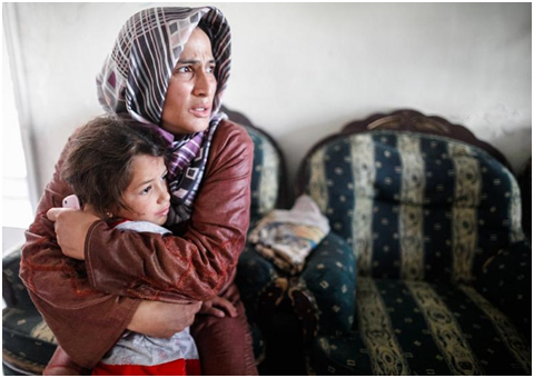 A woman and her child take shelter as a jet bombs the streets around her home in, Aleppo, Syria in 2012. Photo: Sam Tarling/Oxfam