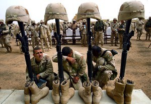 Three U.S. soldiers pay their respects to their fallen comrades after a service held Saturday at the Iraqi National Parade Field to honor eight soldiers from the 2nd Brigade of the 3rd Infantry Division and three journalists who lost thier lives during the U.S.-led war against Iraq. A helmet, rifle and pair of boots represented each soldier while three helmets marked 