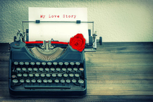Vintage typewriter with white paper and red rose flower. Sample text My Love Story. Vintage style toned grungy picture