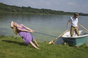 Young girl pulling boat with boy in it to shore