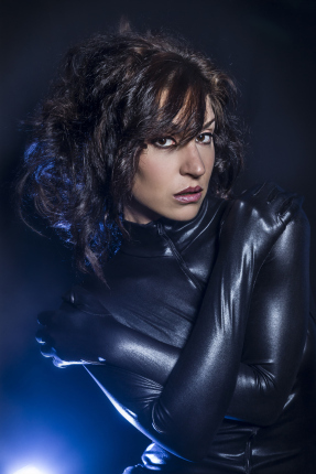 6043276 beautiful brunette woman wearing latex dress on dark bac