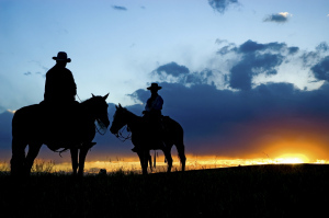 Cowboys, in silhouette, against a dawn sky in Montana