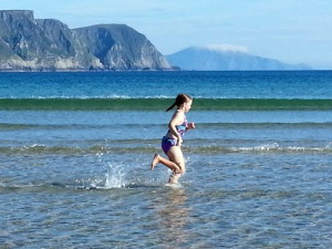 Photo of girl running in the water at the beach